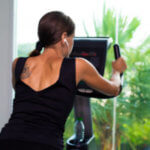 Exercise bike cardio workout at fitness gym of woman taking weight loss. female listens to music on headphones. Athlete builder muscles lifestyle.