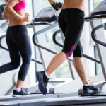 friends  exercising on a treadmill at the bright modern gym