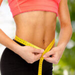 close up of female hands measuring waist