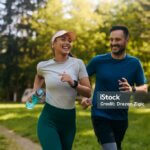 Happy athletic couple having fun while running together in nature. Copy space.